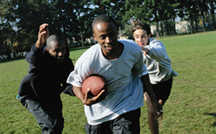 Three young men playing football in an open field