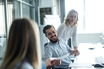 Man passing paperwork to a woman in a conference room