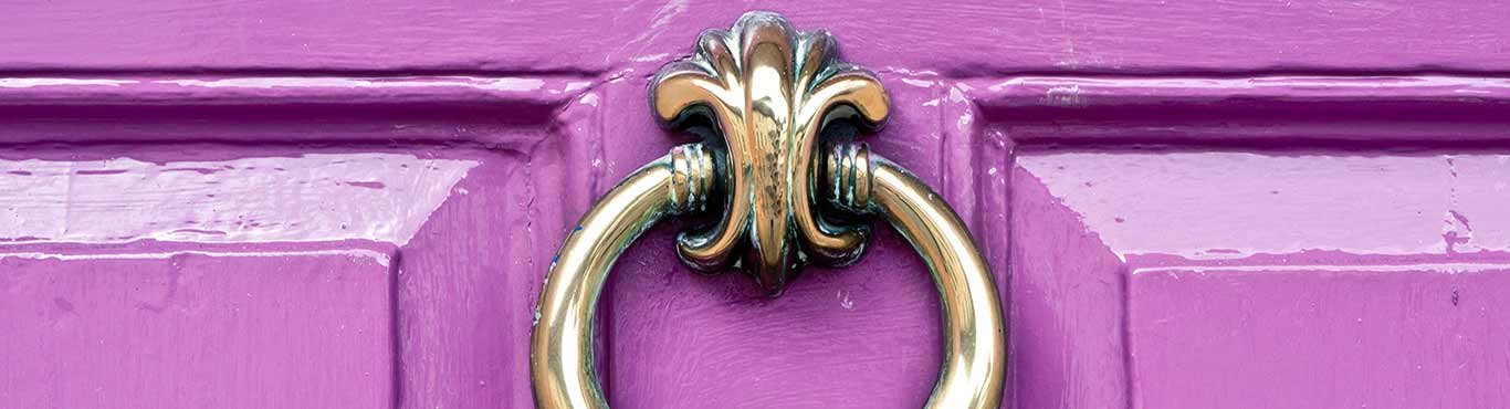 Gold door knocker on a purple door