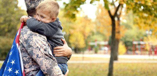 Military dad hugging son