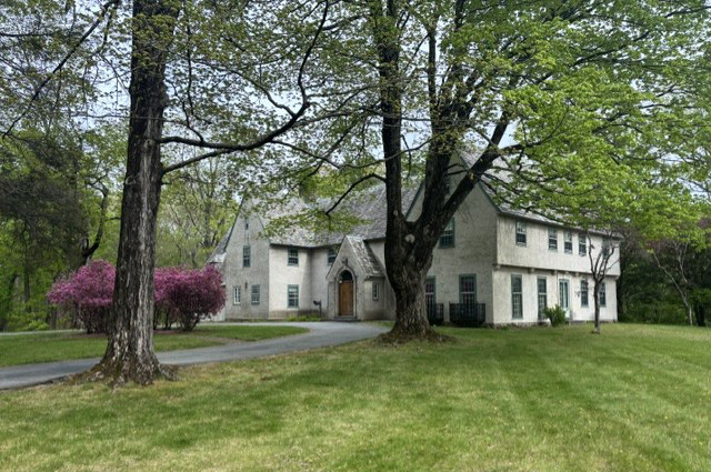 White stone mansion with trees in front