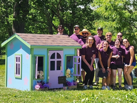 UniBank Explore Program posed next to a playhouse for Operation Playhouse