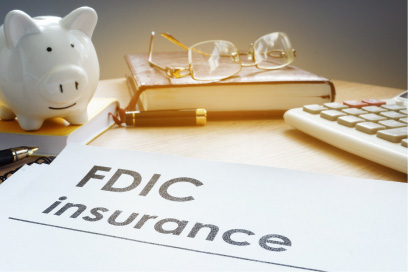 Paper saying FDIC insurance with a piggy bank and calculator behind it